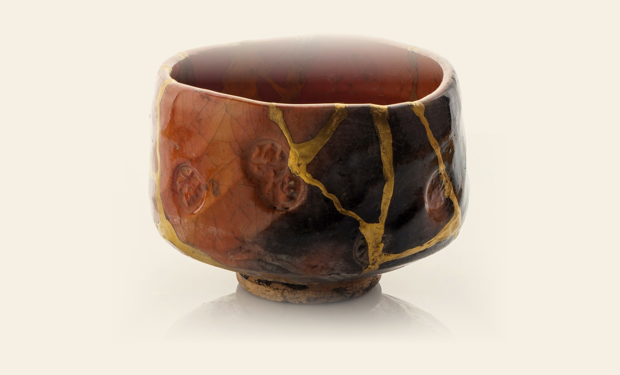 A terracotta tea bowl mended with gold seams, the Japanese repair known as kintsugi